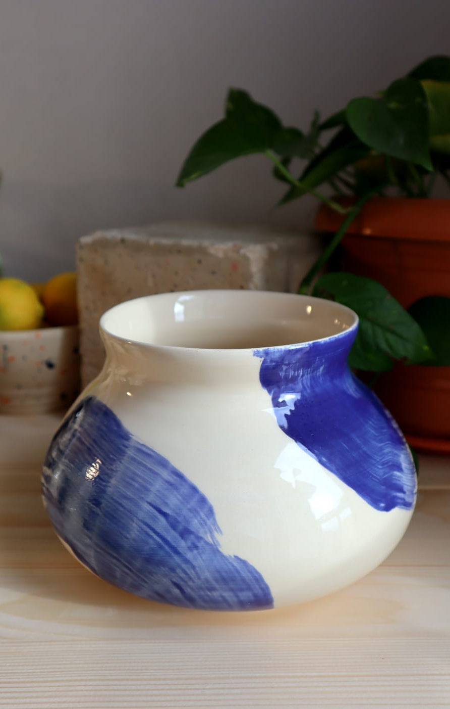 Ceramic vase with blue and white design on a wooden surface with plants in the background